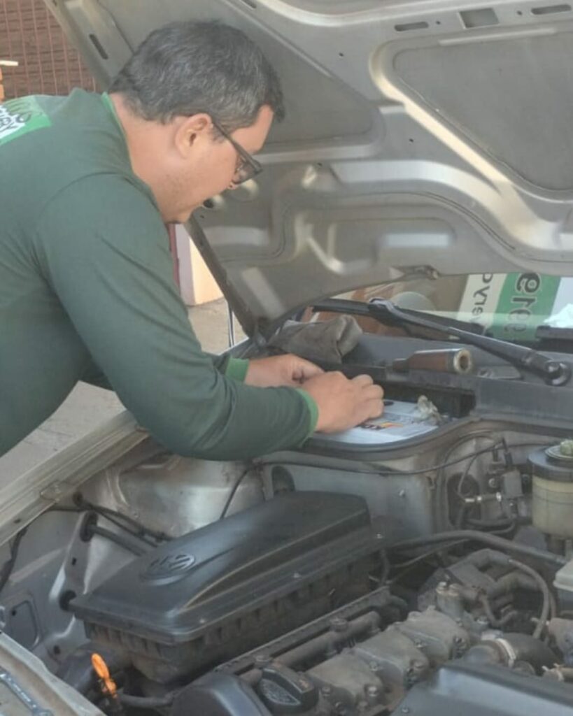 Douglas instalando uma bateria no motor de um carro